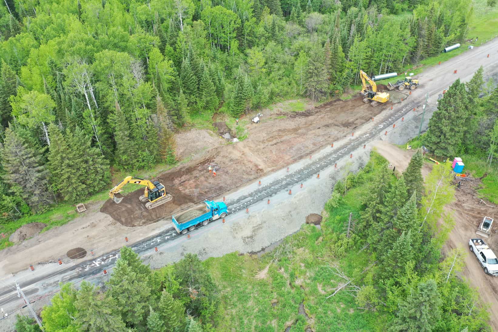 A drone view of renovations on a highway by LH North. Excavators, a blue dump truck, and other machinery stand ready to start the day's work.