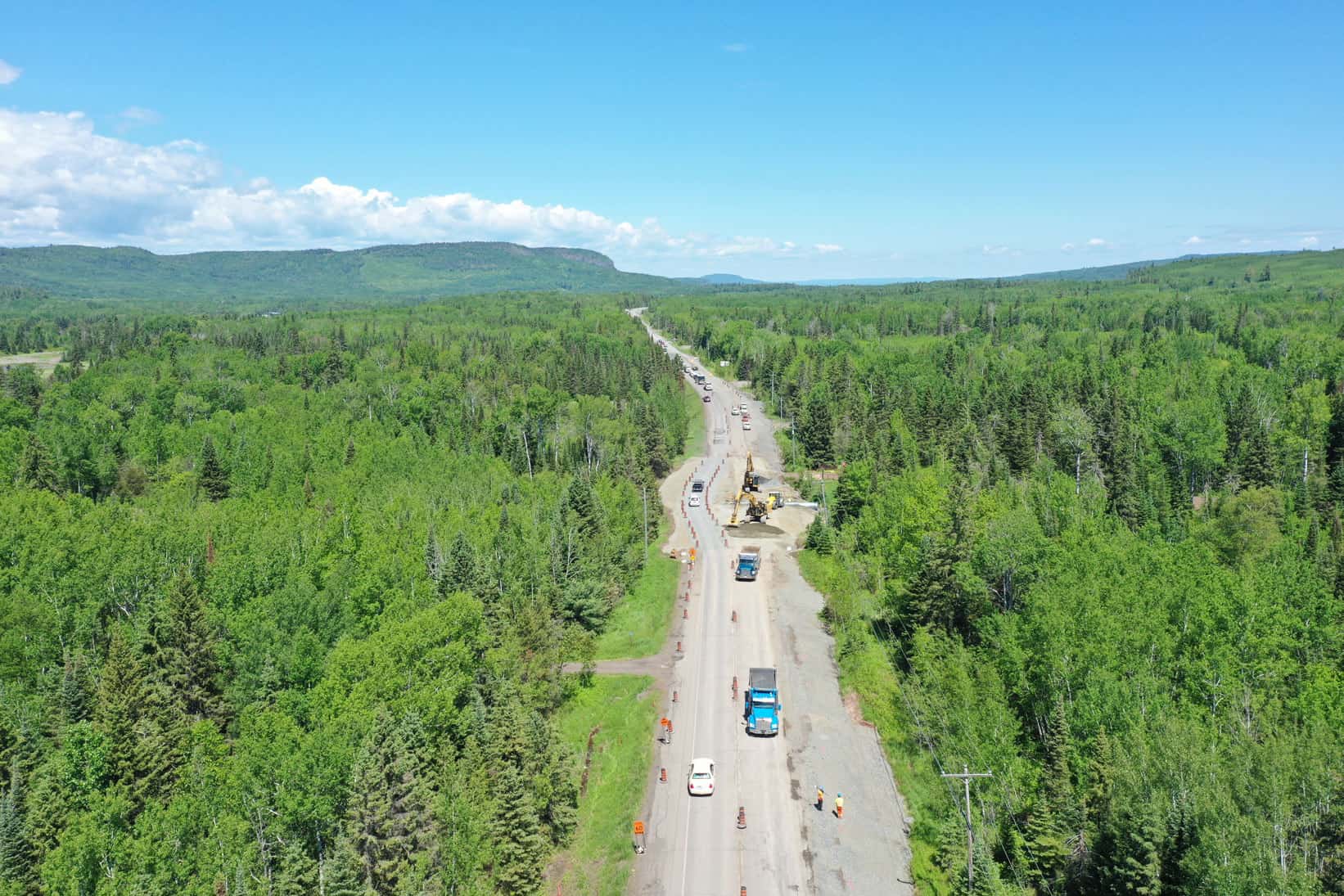 A bird's-eye view of a forest landscape and construction work on a highway by LH North.