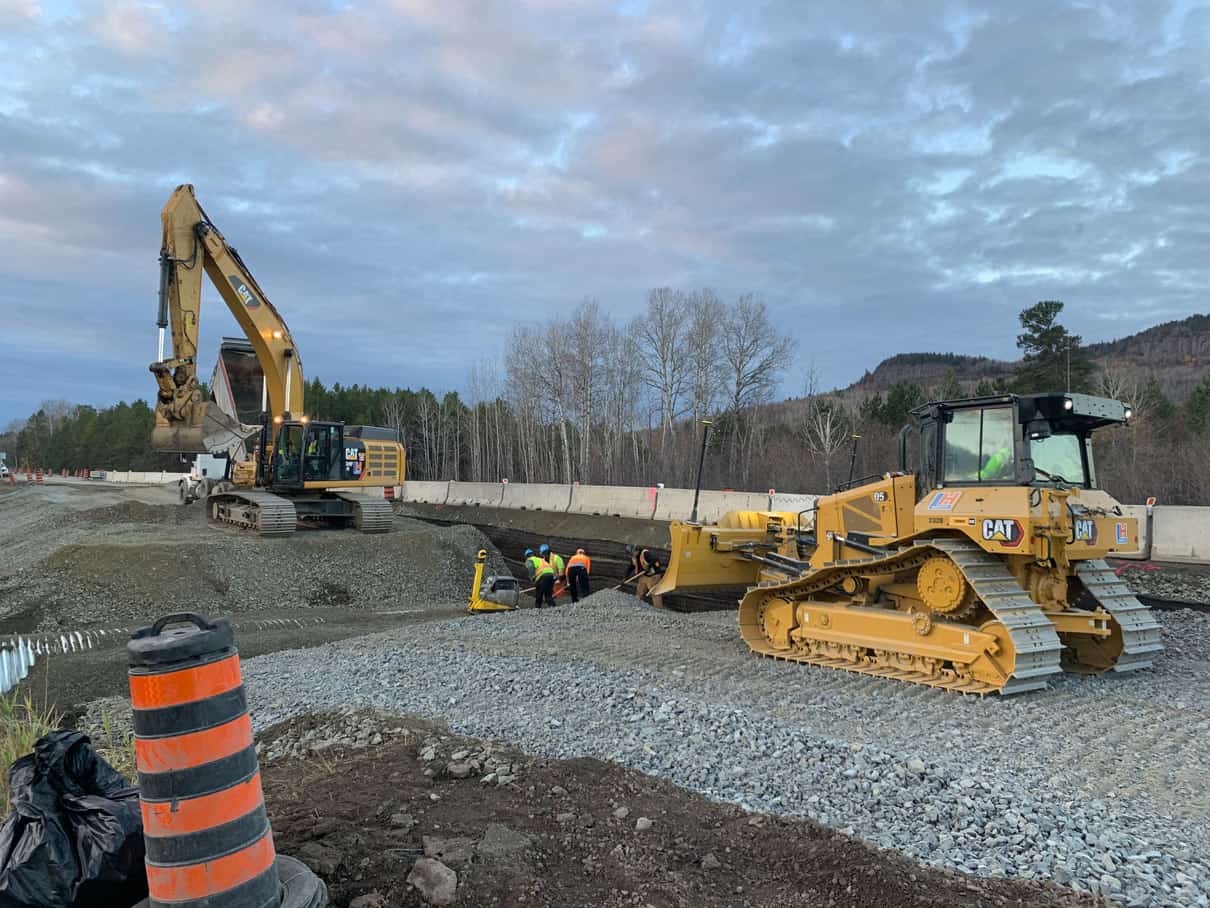 A bulldozer and an excavator working together on an LH North highway construction site.