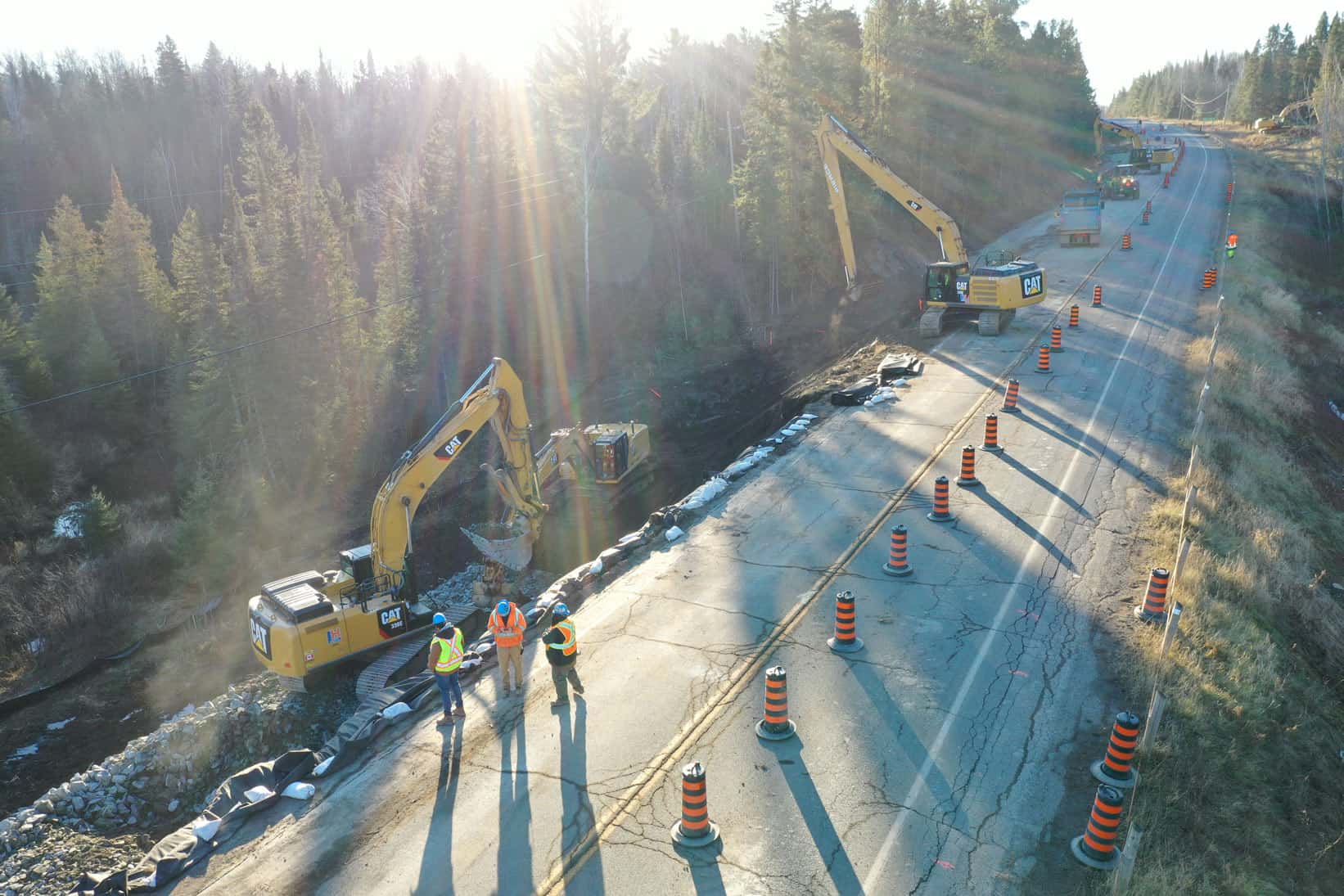 Black and red safety cones stretch as far as the eye can see in this image. Heavy construction machinery lines the side of a motorway in a new highway construction by LH North.
